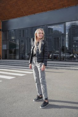 Siyah ceket ve kot pantolon giymiş güzel bir kadın.