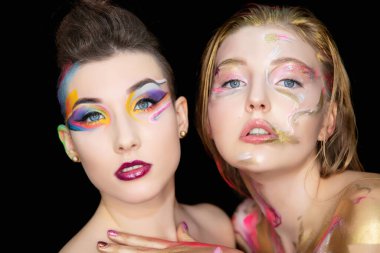 Stüdyoda poz veren yaratıcı makyajlı iki çekici genç kadın..