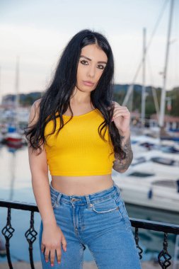 Deniz ve yatın arka planında poz veren çekici bir kadının portresi.
