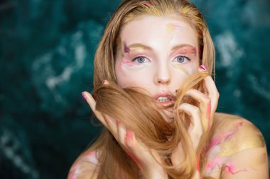 Yüzünde yaratıcı bir makyajı olan sevimli bir sarışının portresi.
