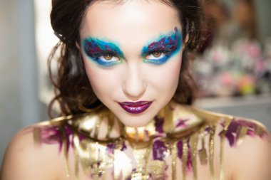 Güzel, genç esmer, yaratıcı makyajlı ve vücut boyalı.