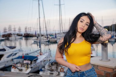 Deniz ve yatın arka planında poz veren genç bir esmerin portresi