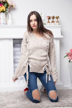 Pantolon ve şöminenin yanında poz veren genç, çekici bir esmer.