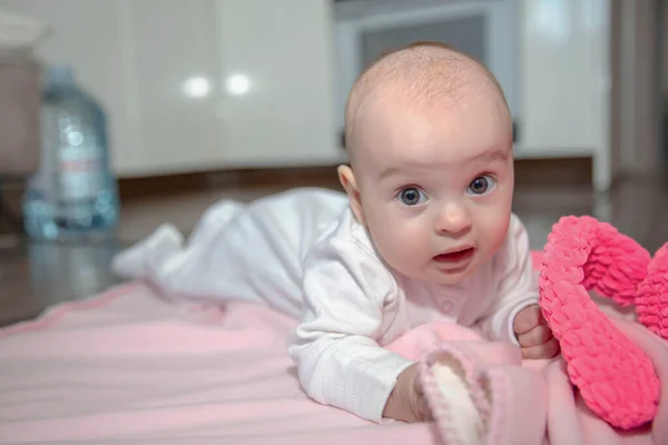 白いスライダーと帽子で身に着けている魅力的な小さな赤ちゃんはピンクのプレイに横たわっています — ストック写真