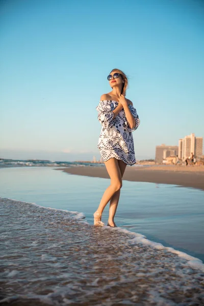 かわいい女性は 水の中に立ってビーチにポーズ チュニックと眼鏡をかけて ストック写真
