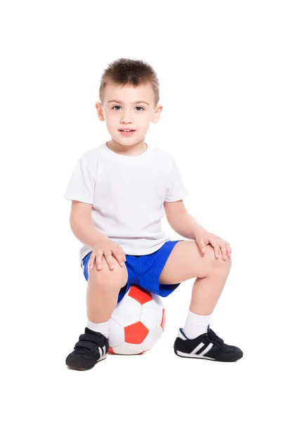 Boy in football uniform sitting on ball — Stock Photo, Image