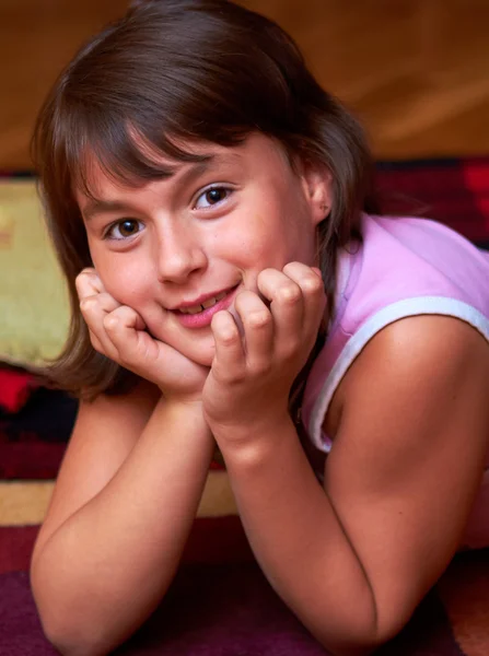 Smiling girl lying on the floor resting his head in hands — Stock Photo, Image