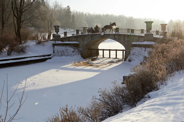 Paesaggio soleggiato invernale con carrozza trainata da cavalli sul vecchio ponte — Foto Stock