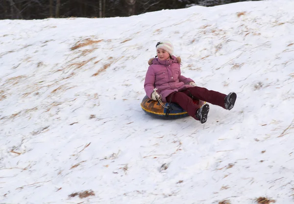 Heureux adolescent fille glissant vers le bas sur neige tube — Photo