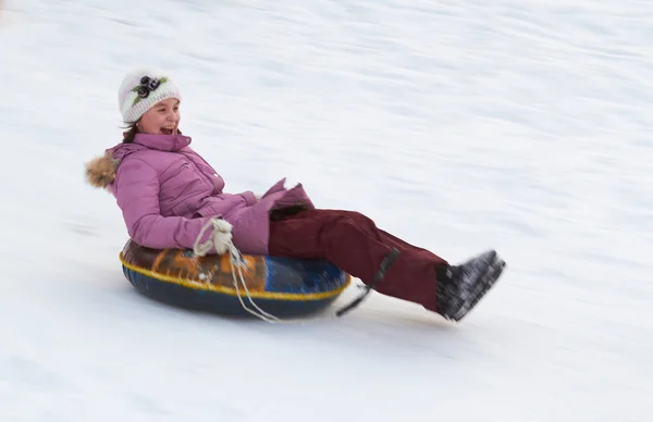 Menina adolescente feliz deslizando para baixo no tubo de neve — Fotografia de Stock