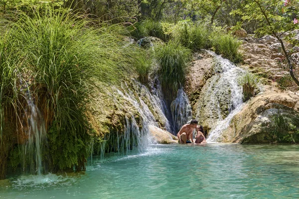 Couple hugging and kissing under waterfall — Stock Photo, Image