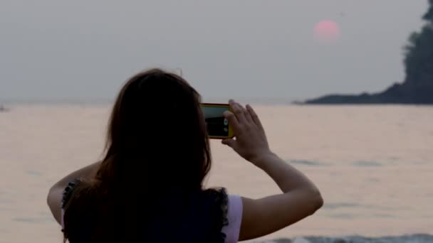 Silhouette des Mädchens, das einen orangen Sonnenuntergang fotografiert — Stockvideo