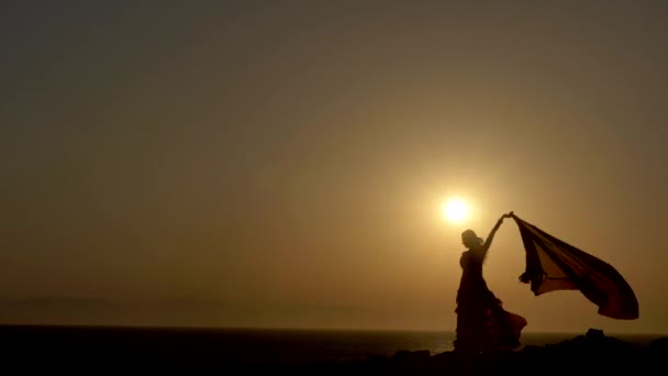 Una silueta de una danza del vientre de la mujer en la puesta del sol hermosa — Vídeo de stock