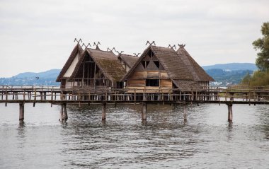 Pfahlbaumuseum Unteruhldingen. Almanya 'nın Unteruhldingen kentindeki Constance Bodensee Gölü' ndeki arkeolojik açık hava müzesinde Stilt evleri ve ahşap köprüler