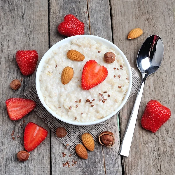 El desayuno. Harina de avena con fresas y frutos secos — Foto de Stock