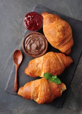 Classic croissants with chocolate topping and berries jam on black tables. Top view  croissants. Breakfast.