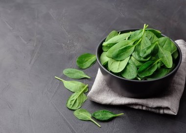 Fresh spinach salad in black plate on black concrete tables.