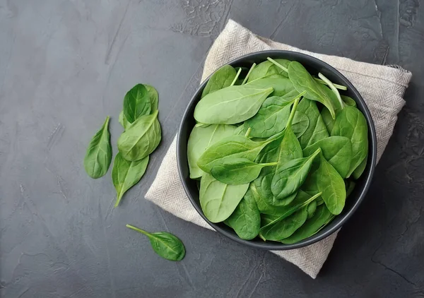 Fresh baby spinach salad on black concrete tables.
