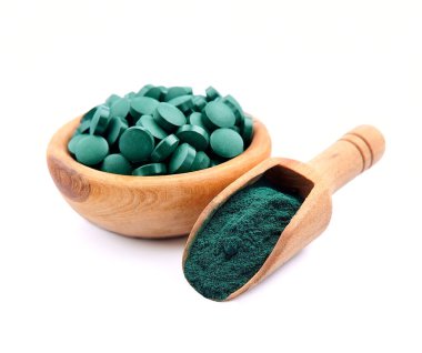 Beyaz arka planda, ahşap plaka içerisindeki sarmaşık tozu ve spirulina tabletleri. Sağlıklı gıda takviyesi. Süper yemek malzemesi..