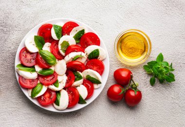 Domatesli İtalyan caprese salatası ve koyu arkaplanda fesleğen yapraklı mozzarella peyniri. Düz yatıyordu.