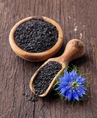 Tahta arka planda nigella sativa çiçeği olan siyah kimyon tohumları.