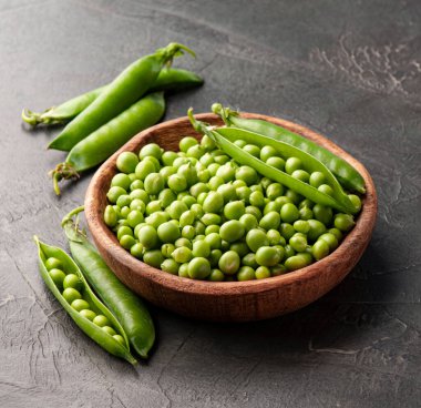 Beton zeminde, ahşap tabakta yeşil bezelyeler..