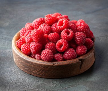 Sweet raspberry in wooden plate on concrete backgrounds.