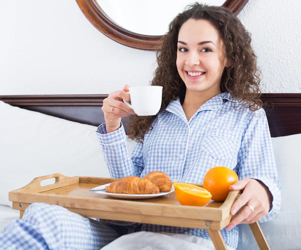 Chica sonriente disfrutando del desayuno en la cama —  Fotos de Stock