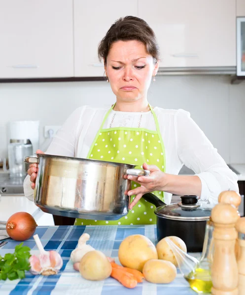 Vrouw kijken naar bedorven voedsel in keuken — Stockfoto