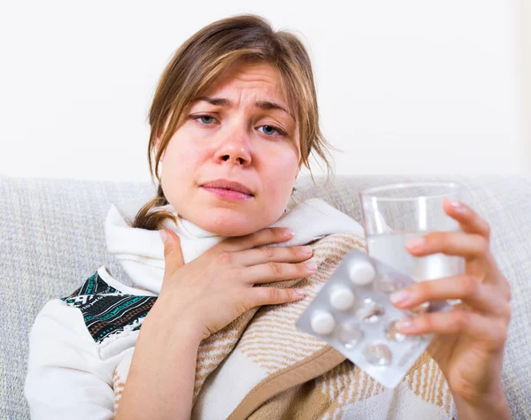 Женщина принимает антибиотики от боли в горле — стоковое фото