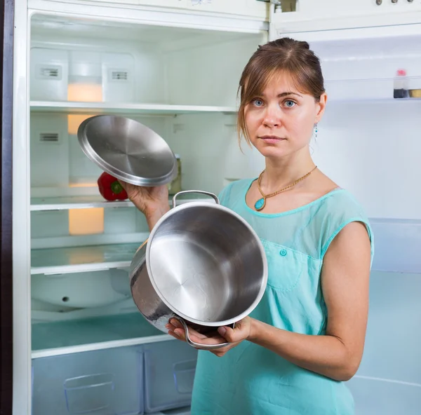 Mujer molesta mirando el refrigerador vacío —  Fotos de Stock