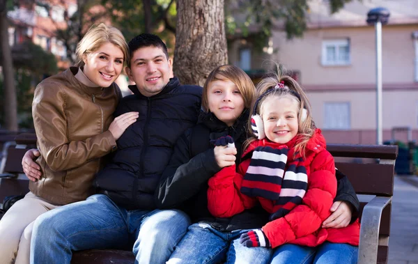 Familjen sitter på bänken utomhus — Stockfoto