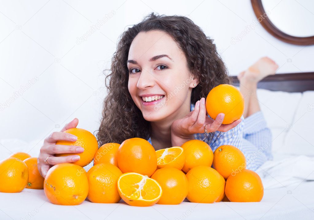 Positive girl eating oranges in bed Stock Photo by ©Jim_Filim 105256178