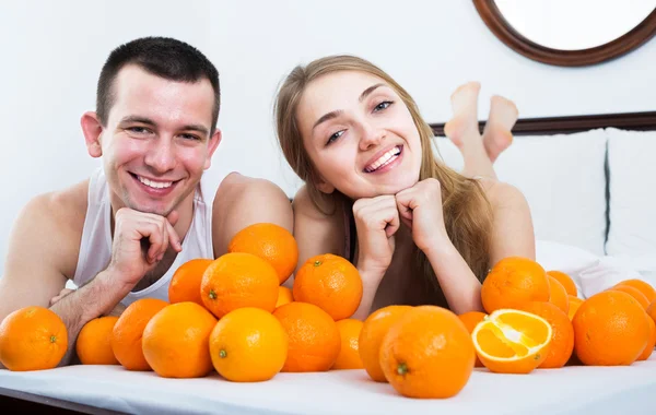 Casal com laranjas na cama — Fotografia de Stock