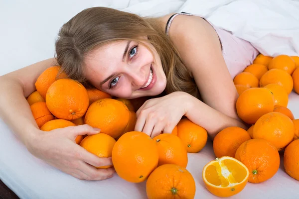 Portret van een meisje met sinaasappelen in bed — Stockfoto