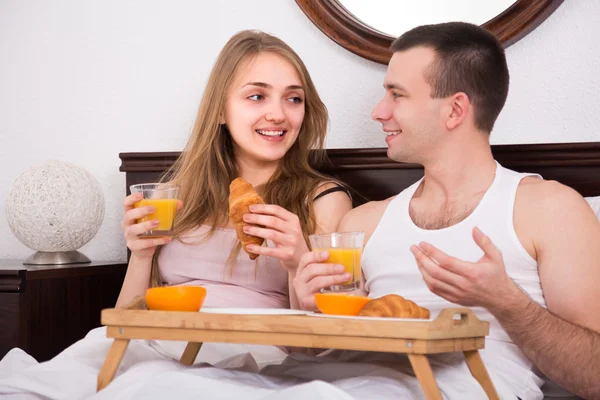 Пара с вкусным завтраком в постели — стоковое фото