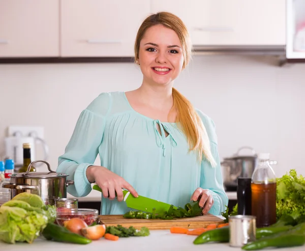 Jeune femme hachant laitue et herbes — Photo