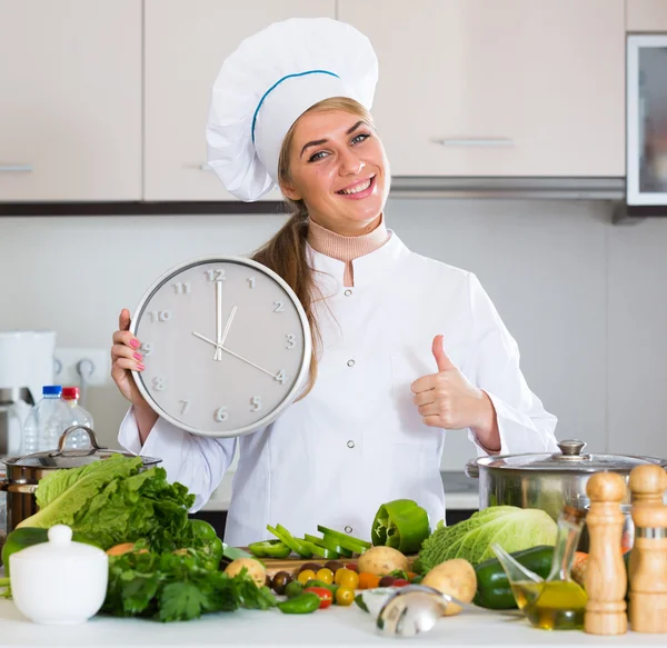 Веселая женщина-повар с часами и овощами — стоковое фото
