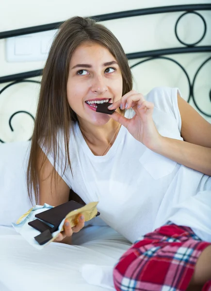 Bruneta se těší čokolády v posteli — Stock fotografie