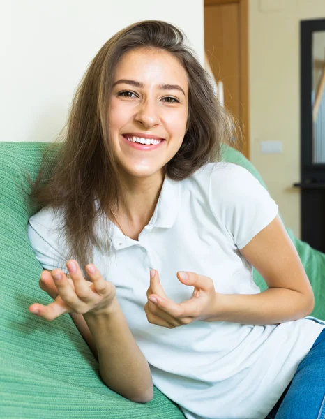 Mädchen gestikuliert, während sie auf der Couch sitzt — Stockfoto