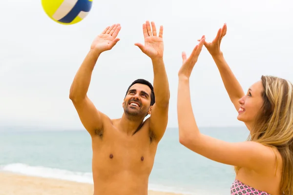 Пара, играющая с мячом на пляже — стоковое фото