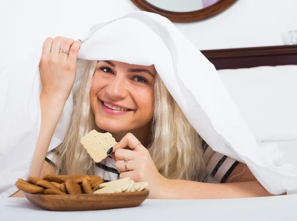 Chica comiendo en secreto galletas en la cama — Foto de Stock