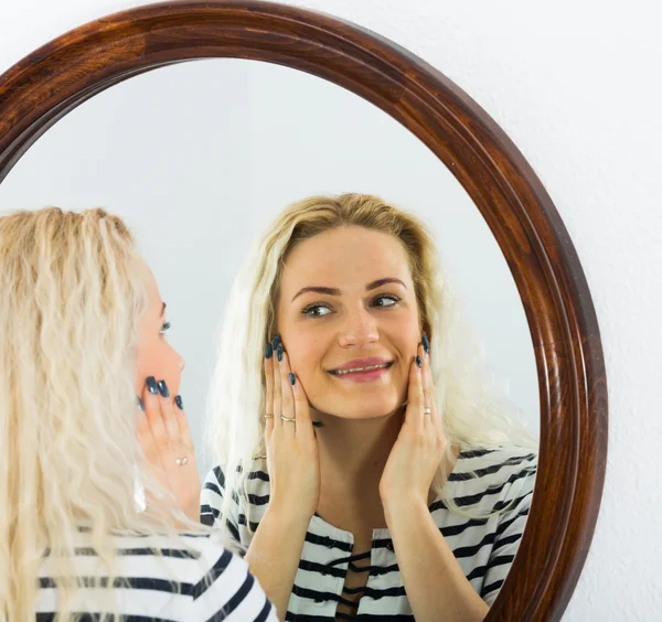 Cute girl watching herself in mirror indoors — Stock Photo, Image