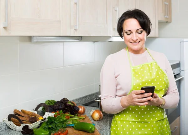 Retrato de ama de casa en delantal recibiendo sms — Foto de Stock