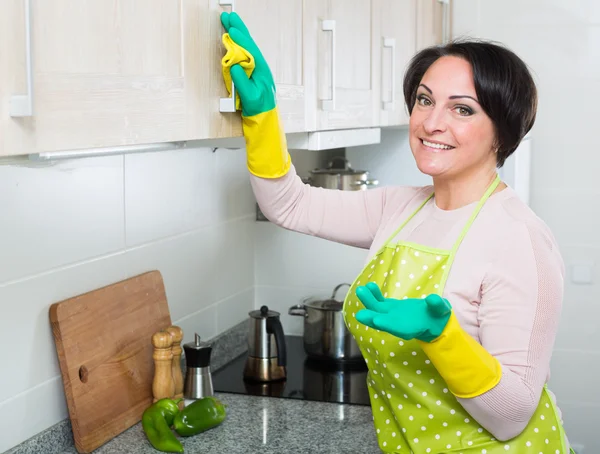 Mulher polvilhar móveis na cozinha — Fotografia de Stock