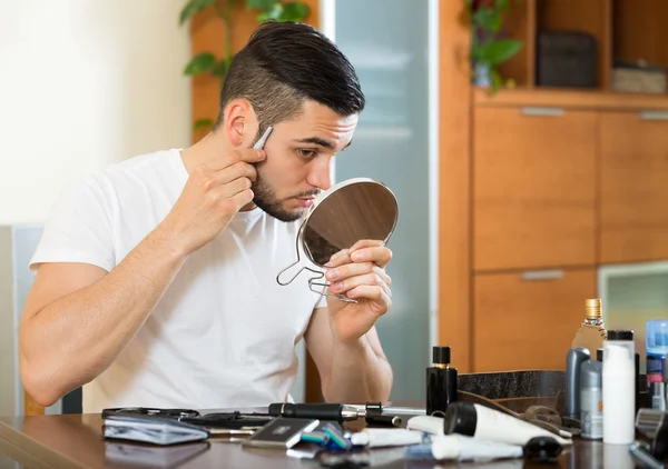 Мужчина бреет лицо триммером — стоковое фото