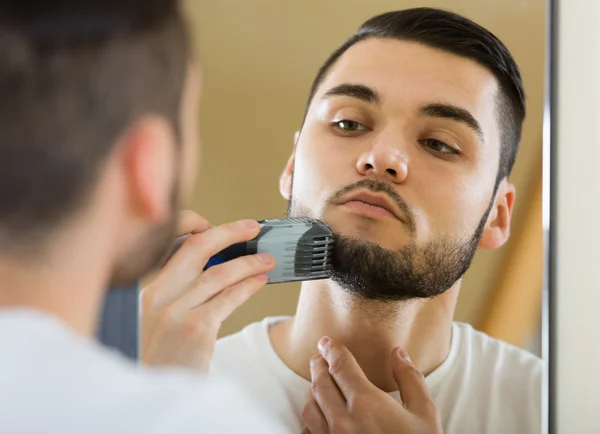 Mann blickt in Spiegel und rasiert sich — Stockfoto