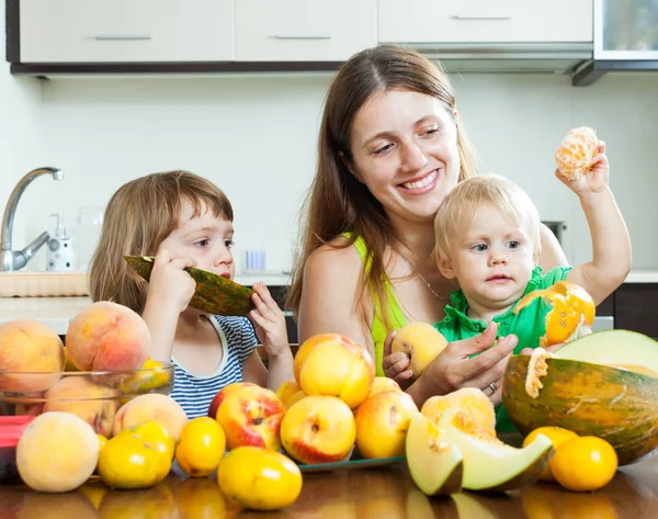 Vrouw met kinderen eten perziken — Stockfoto