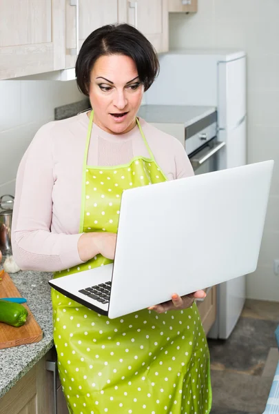 Portrait de femme au foyer dans tablier avec ordinateur portable — Photo