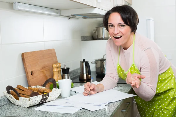 Žena s bankovní dokumenty v kuchyni — Stock fotografie